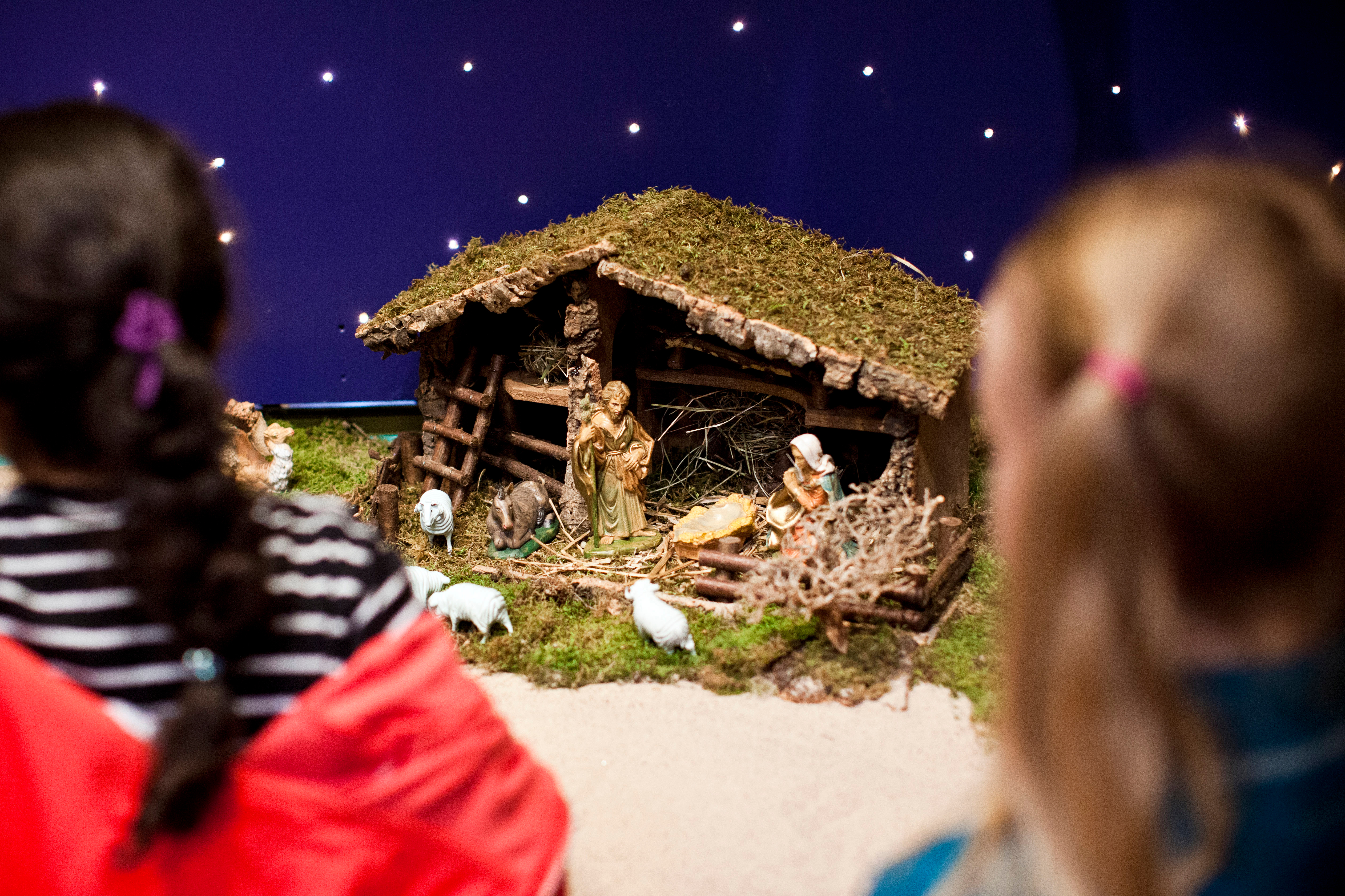 Två flickor står och tittar på en julkrubba.