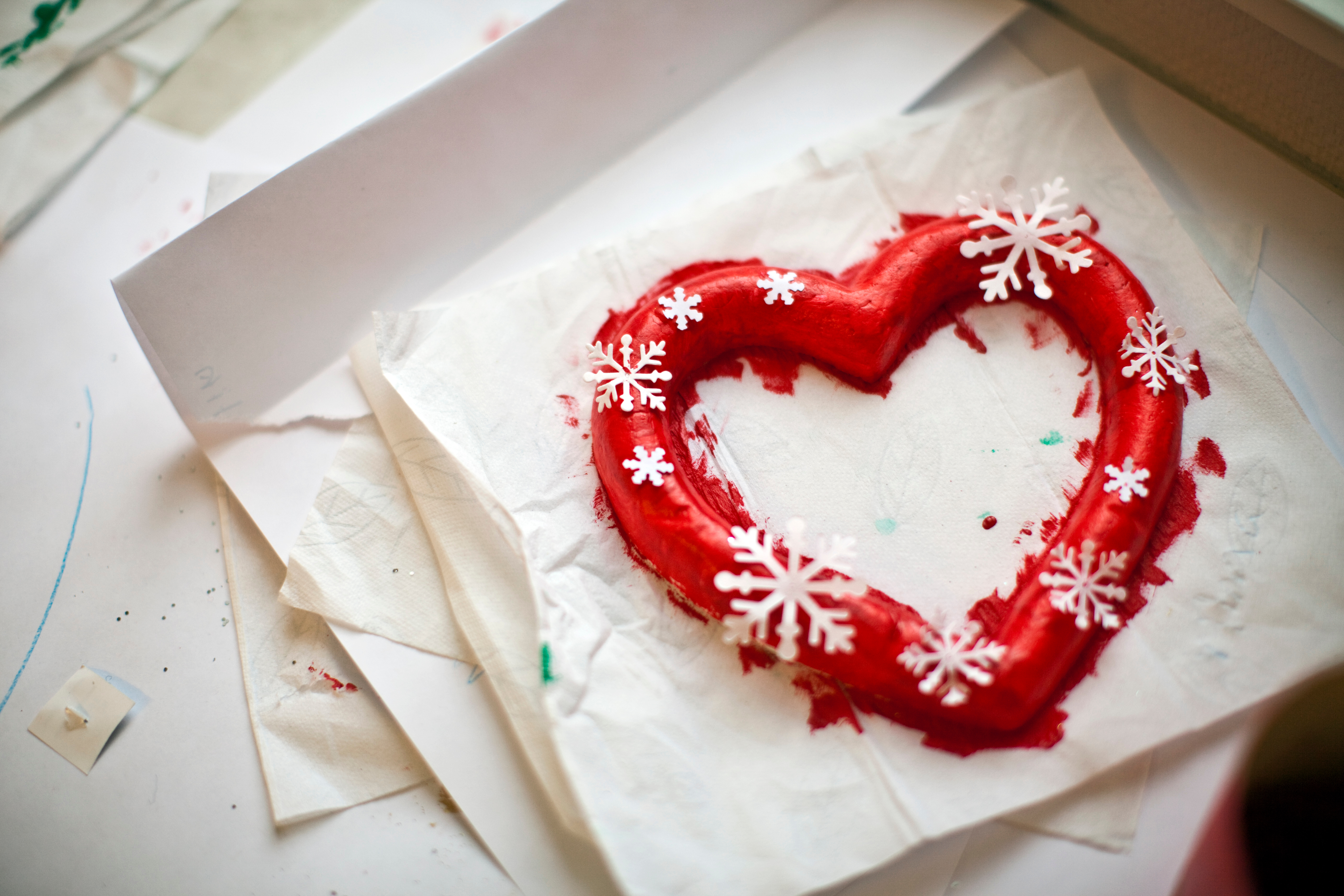 Någon har målat ett gipshjärta med röd färg och limmat på vita snöflingor.