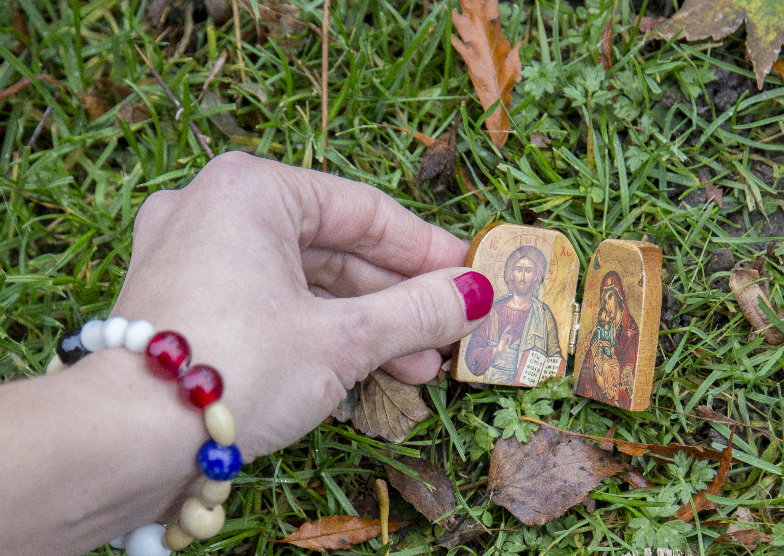 Närbild på någon som lägger en liten träbit med ikonbilder i gräset.