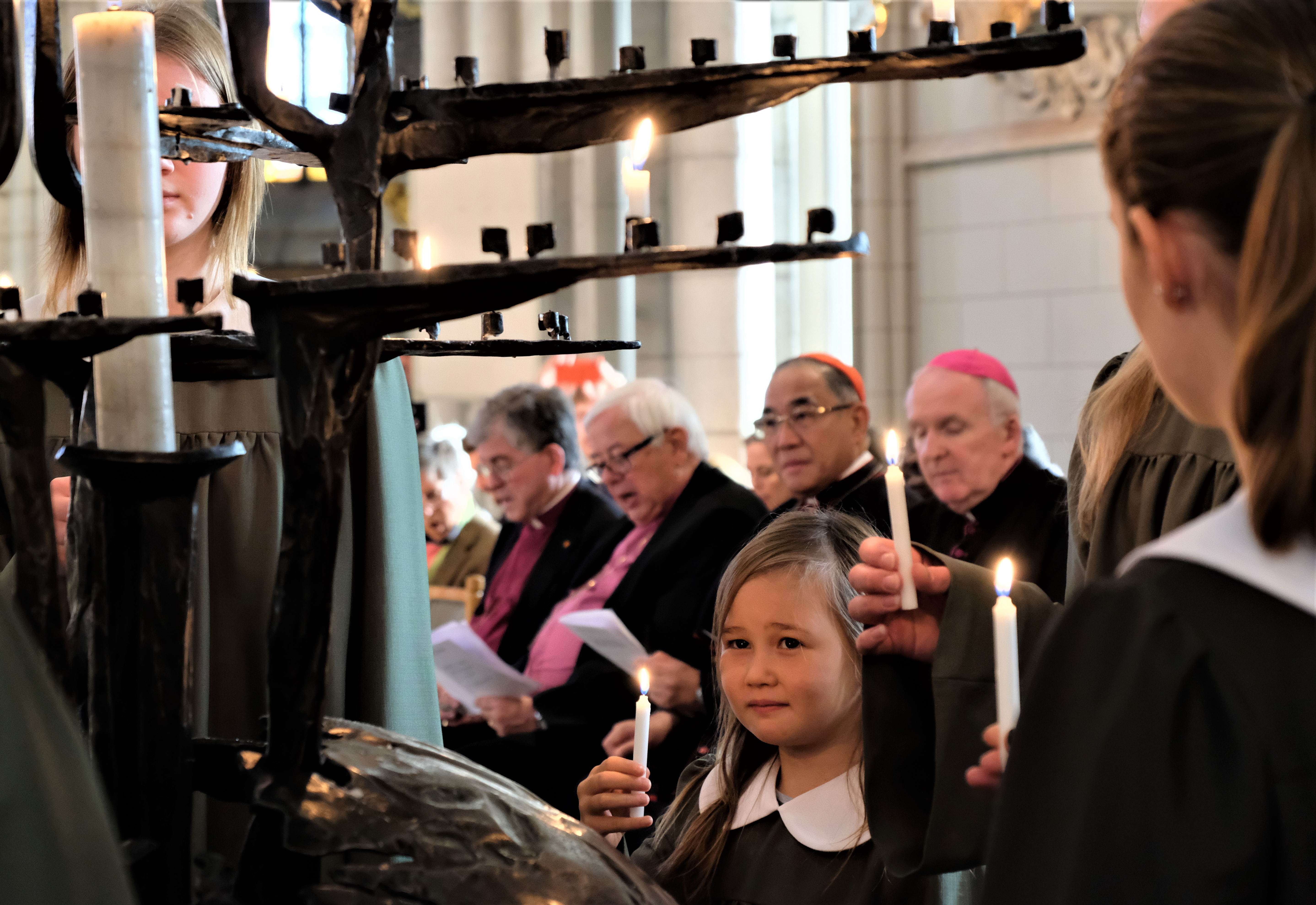 Flickor i svarta kåpor tänder ljus i Uppsala domkyrka.