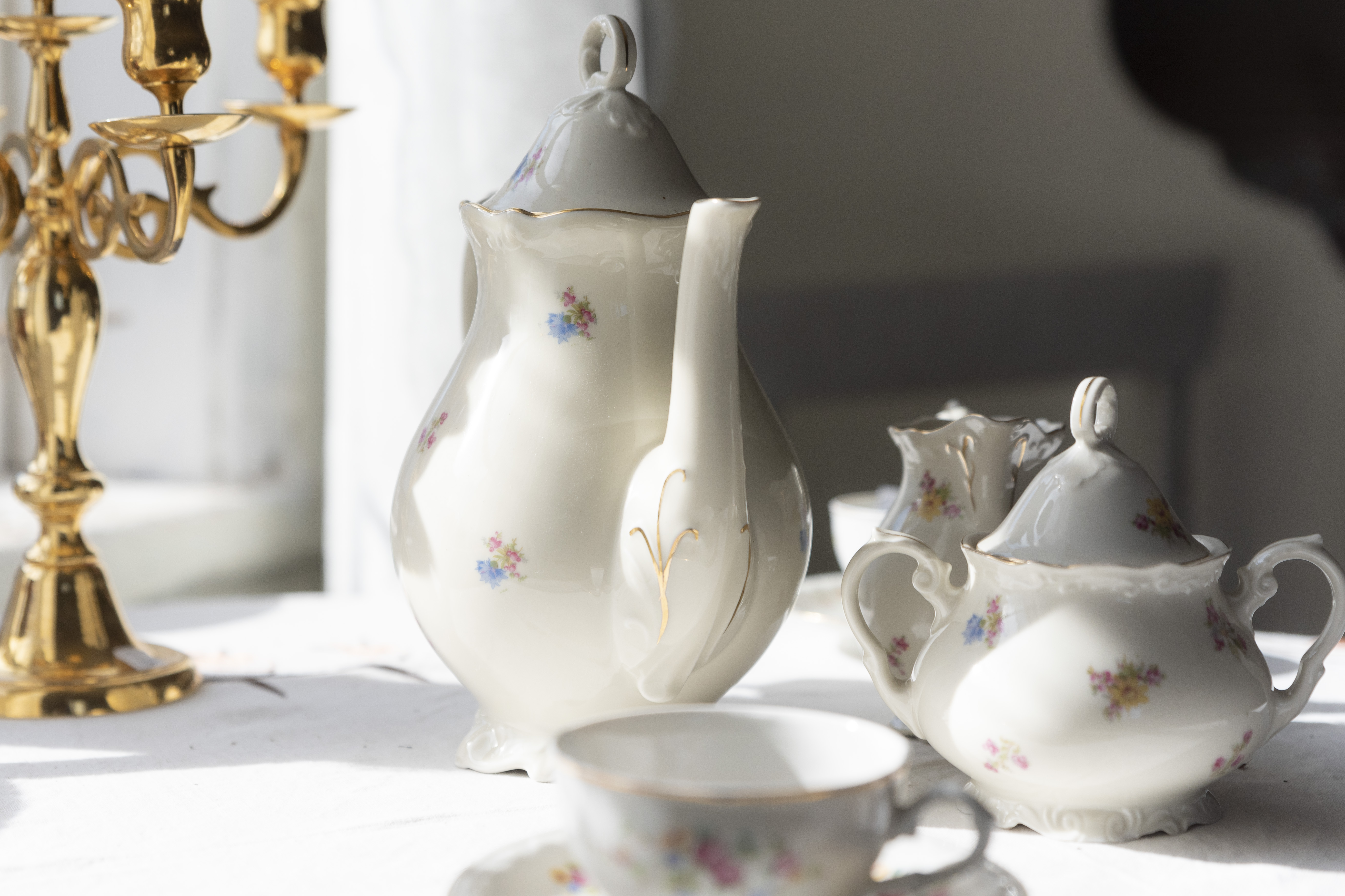 En gammal kaffeservis i vitt porslin med guldkant står framdukad.