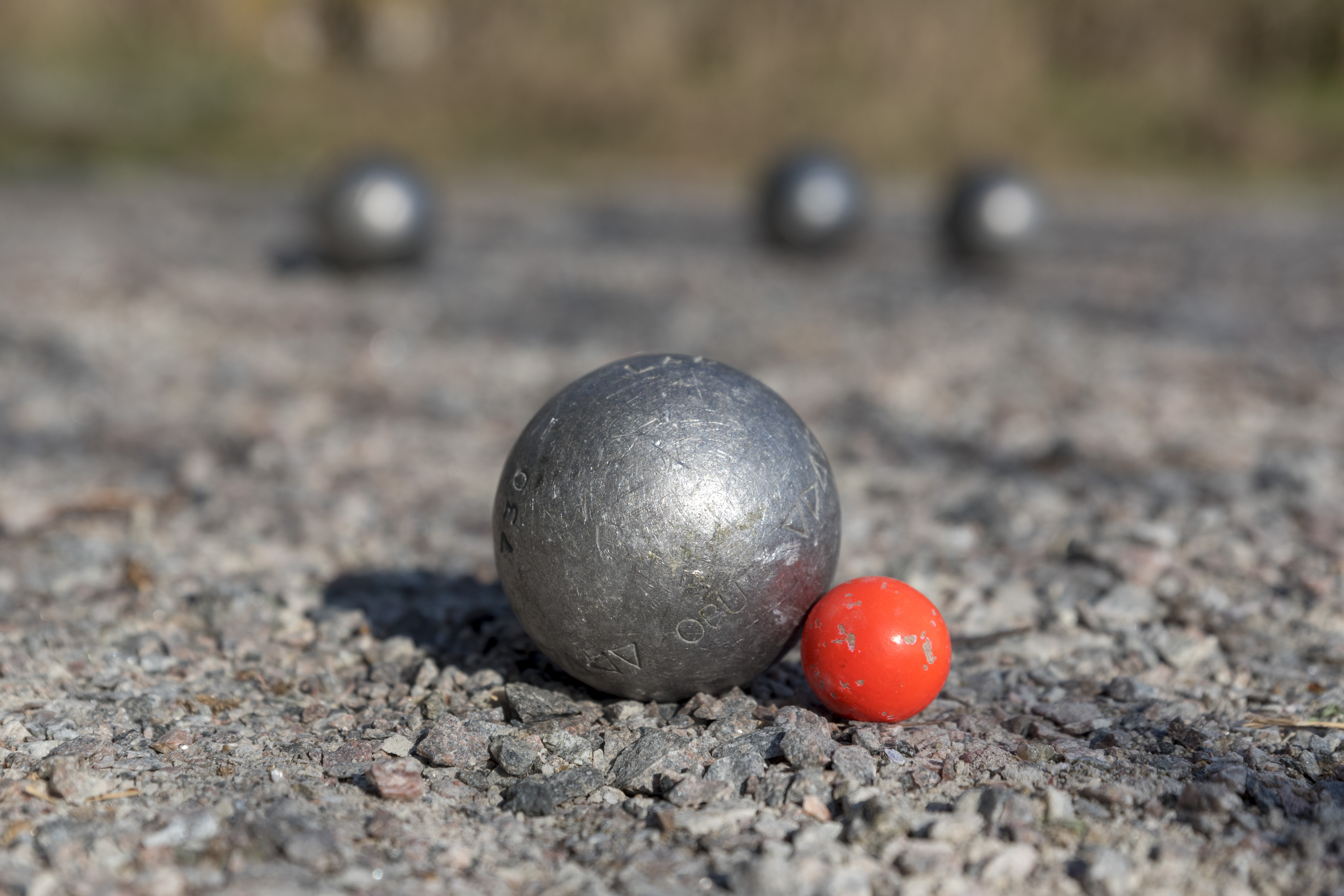 Ett bouleklot ligger precis vid den röda kulan på grusbanan.