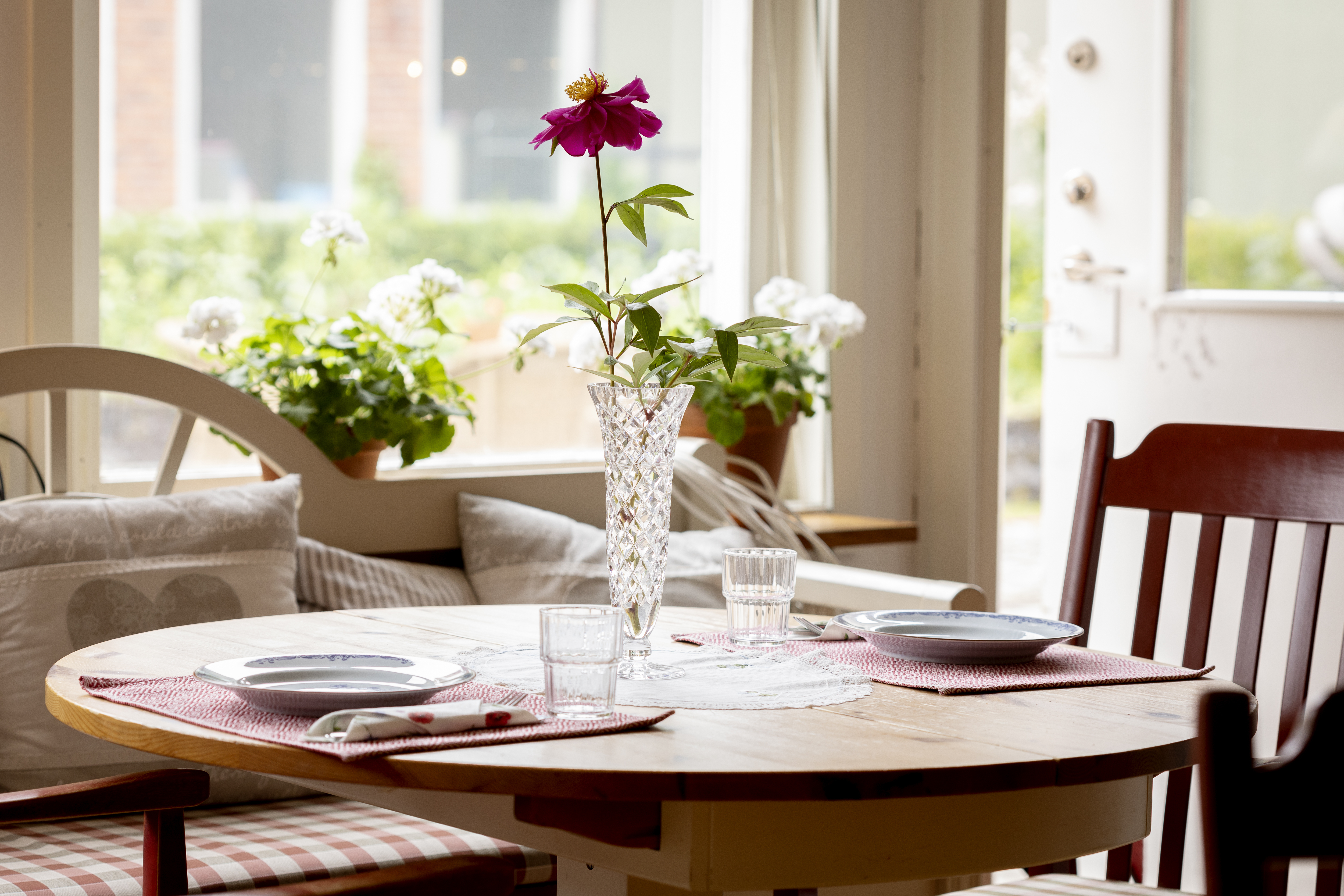 Ett bord dukat för två, med en ensam blomma i en vas mitt på.