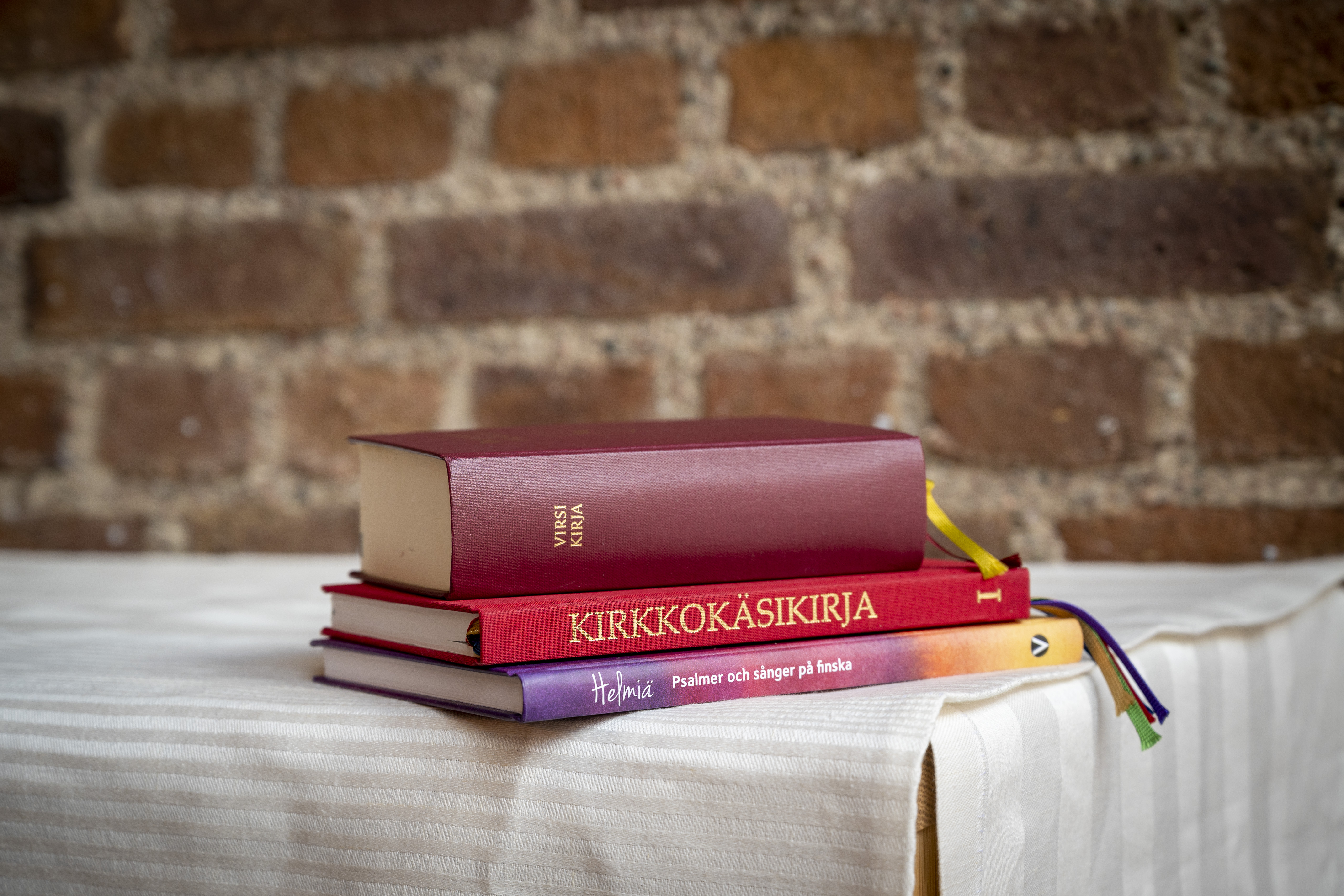 En finsk kyrkohandbok och två psalmböcker ligger på kanten av ett altare.