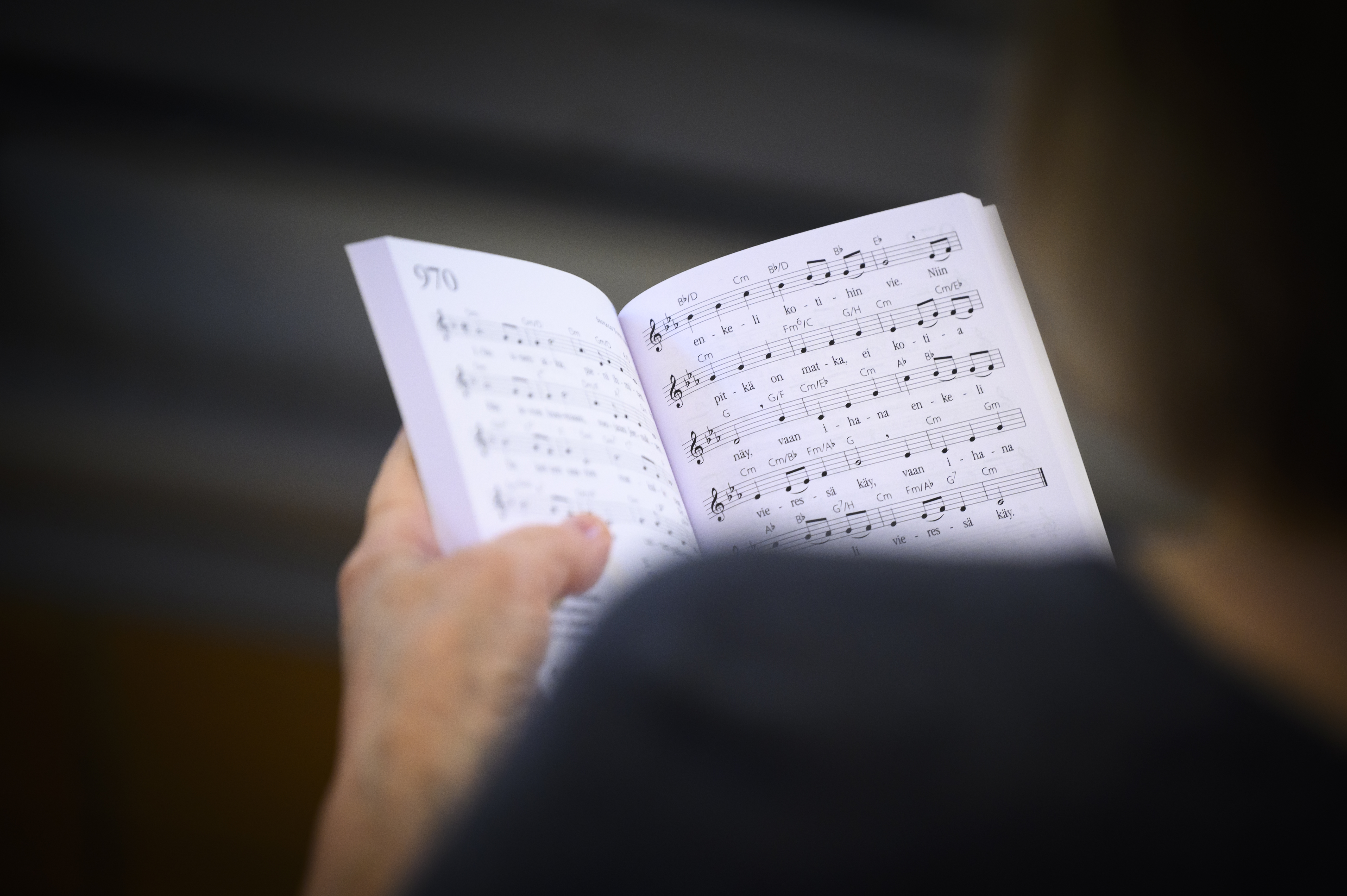 En person håller i en uppslagen psalmbok.