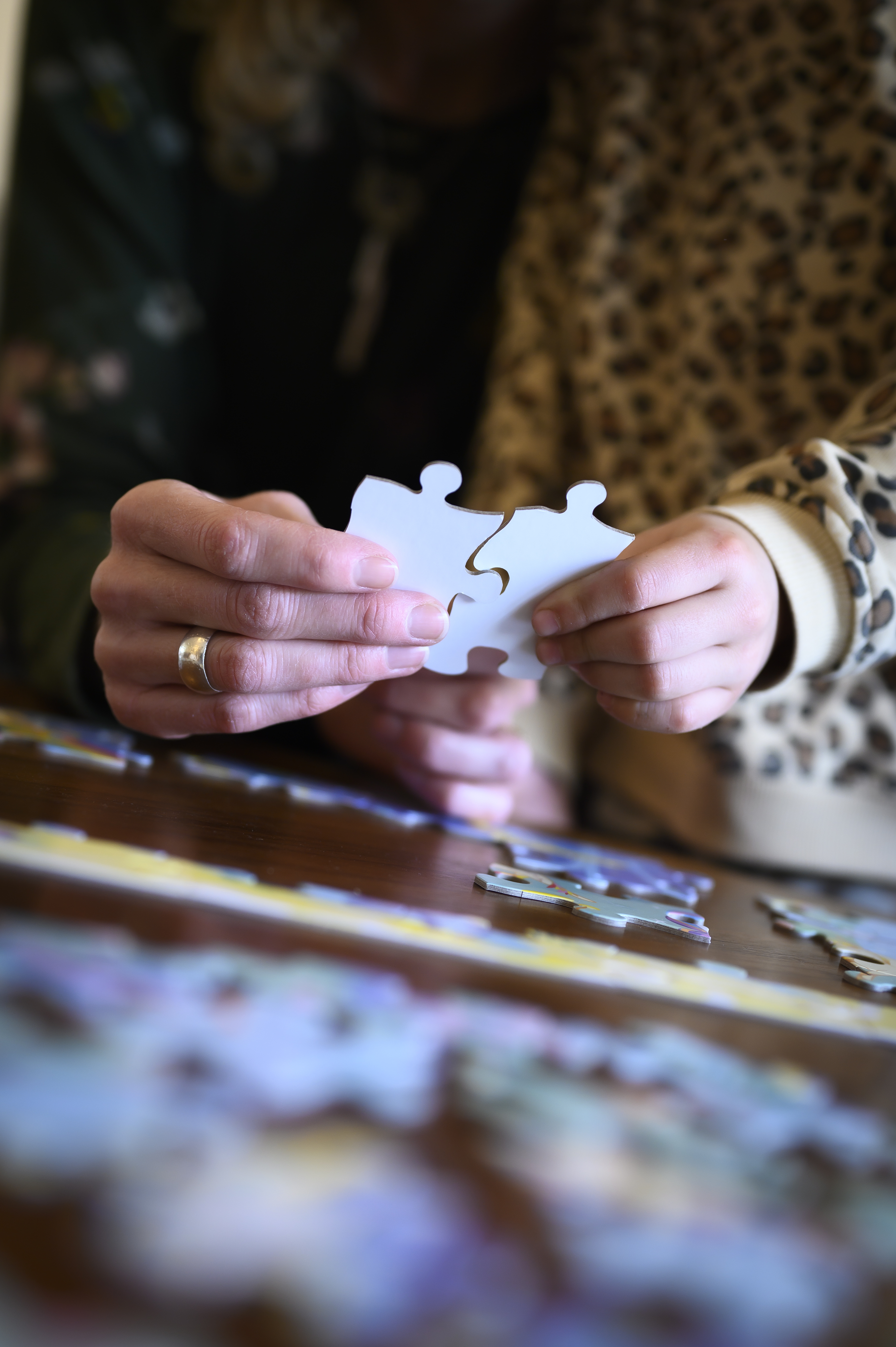 En vuxen och ett barn lägger pussel tillsammans.