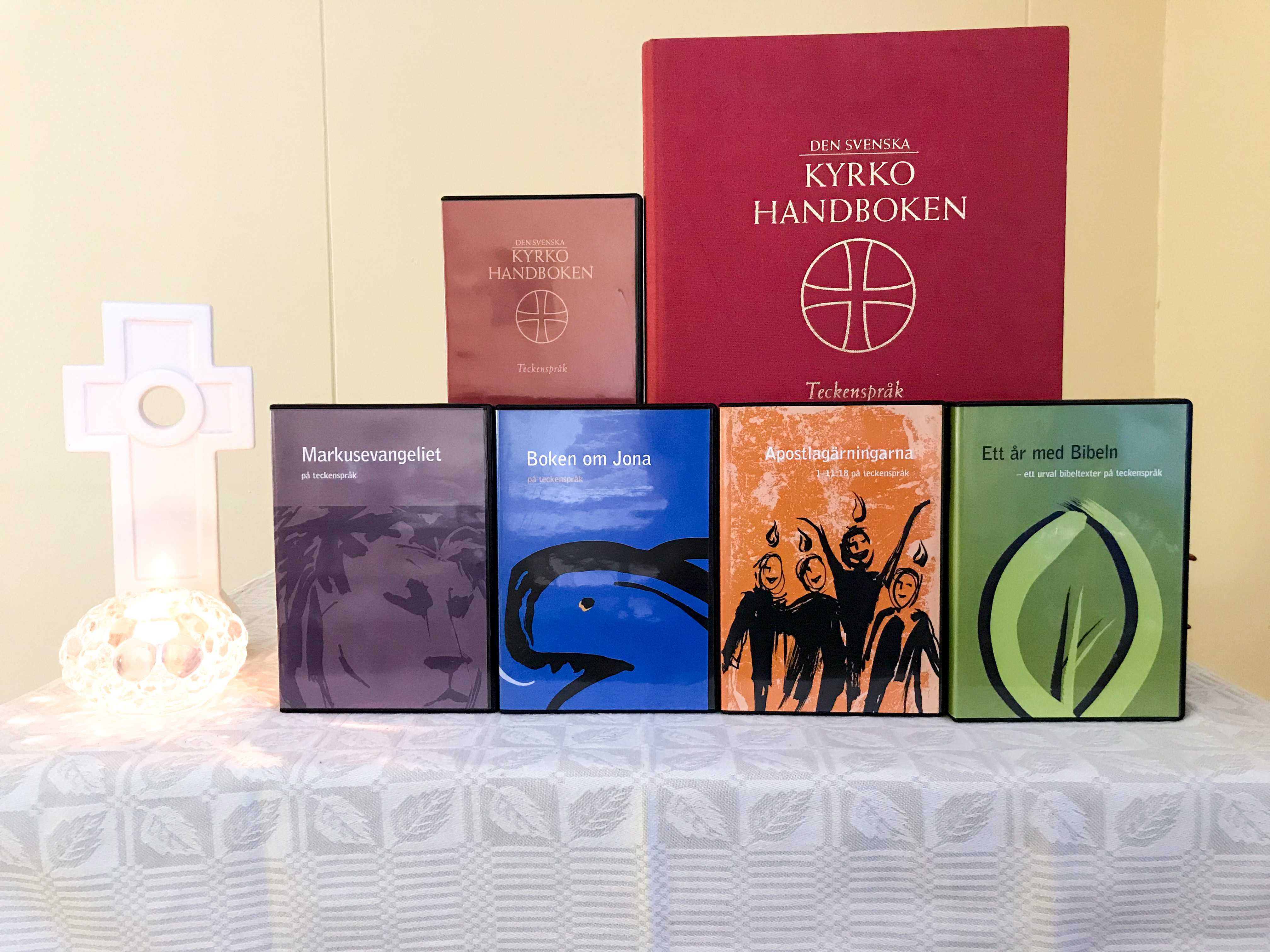 Delar av bibeln och kyrkohandboken på teckenspråk och som ljudböcker står uppställda på ett bord.