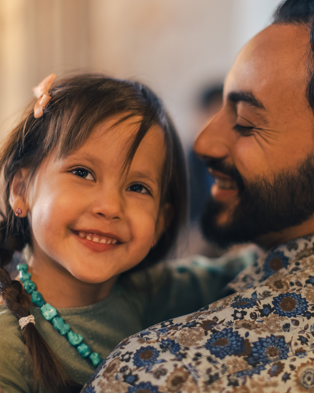 En flicka omfamnas av sin pappa och ler.