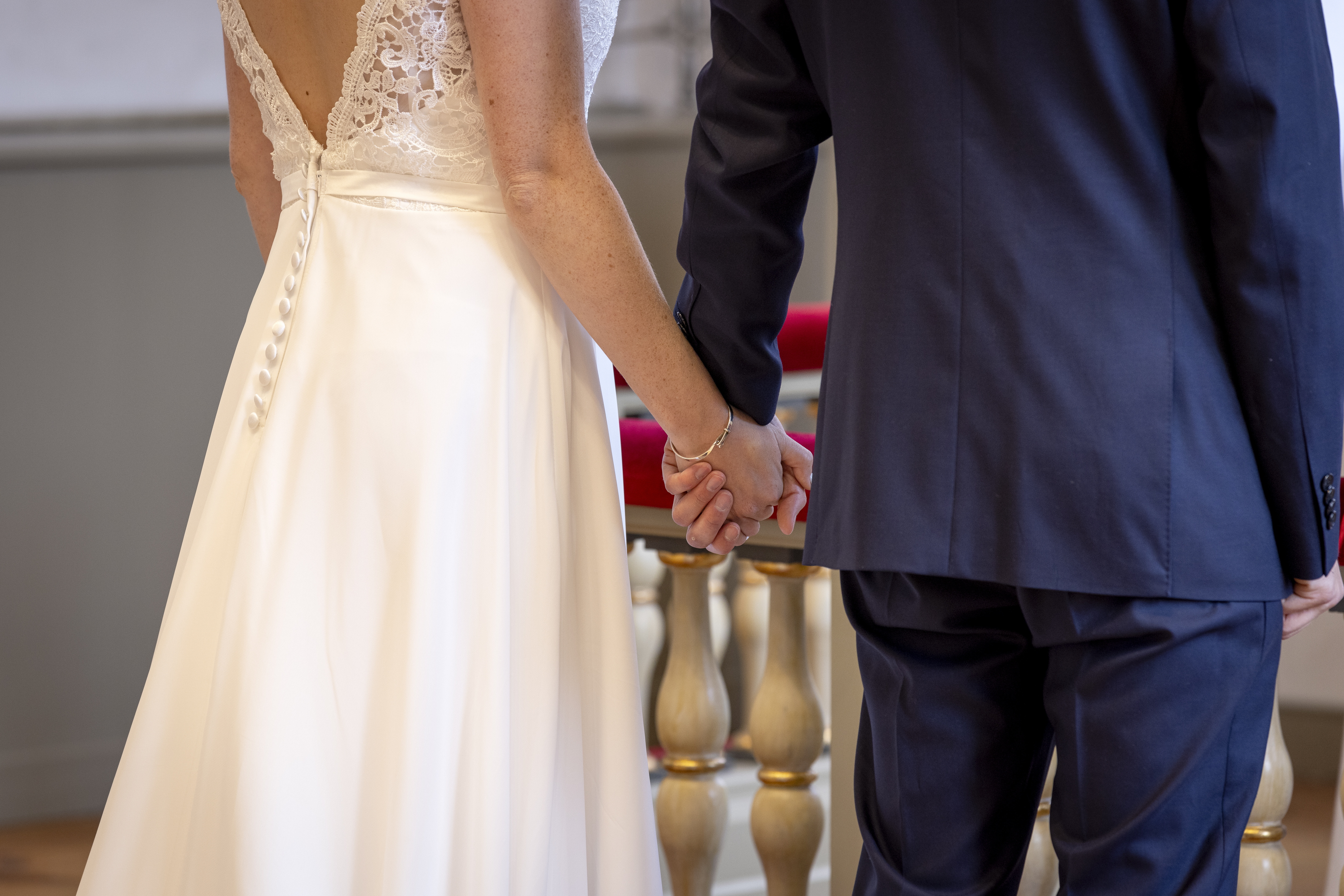 Drop-in vigsel i en kyrka. Ett brudpar står vid altarringen med ryggen mot kameran och håller varandra i handen.