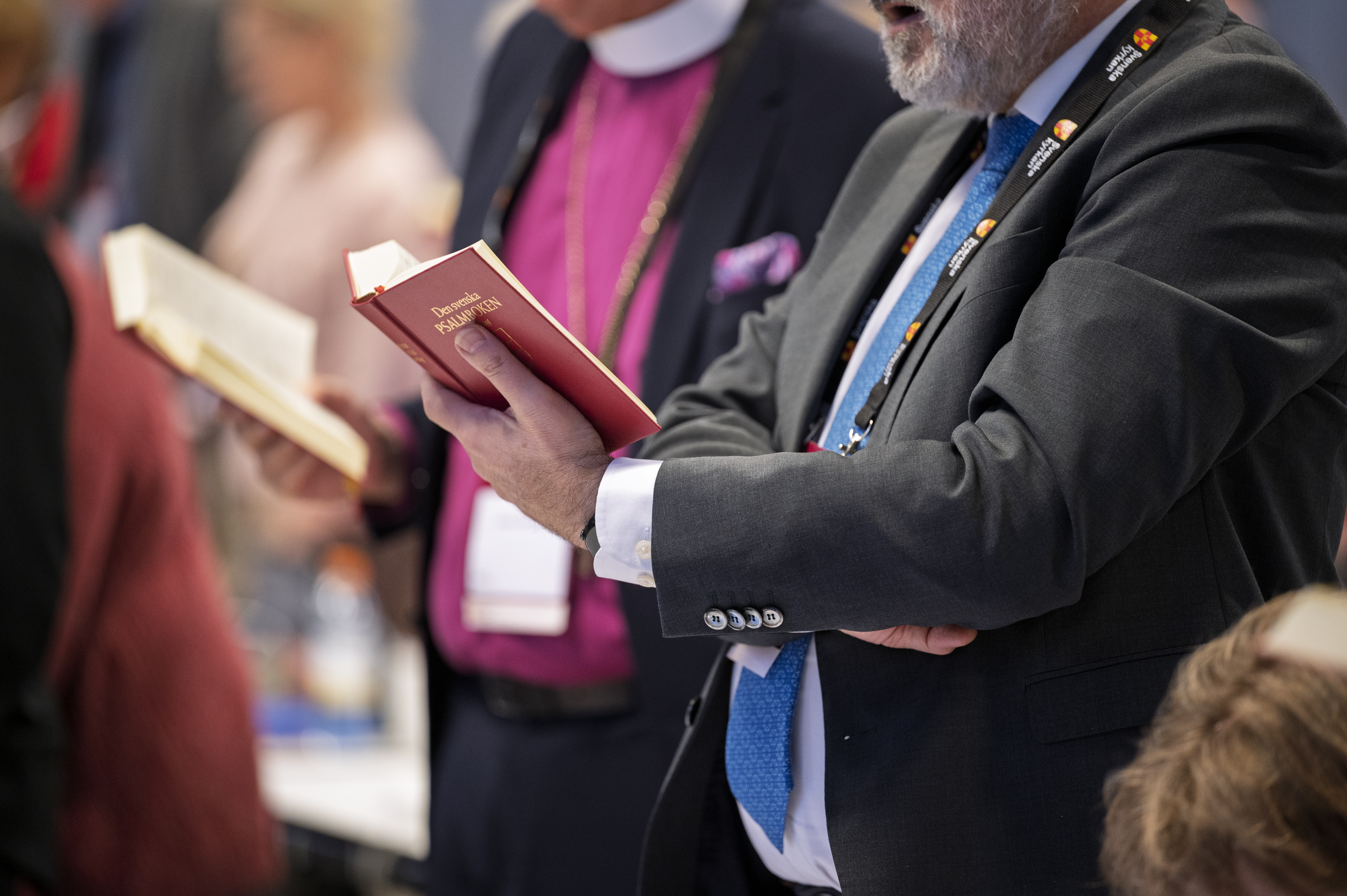 Några personer står med uppslagna psalmböcker i händerna.