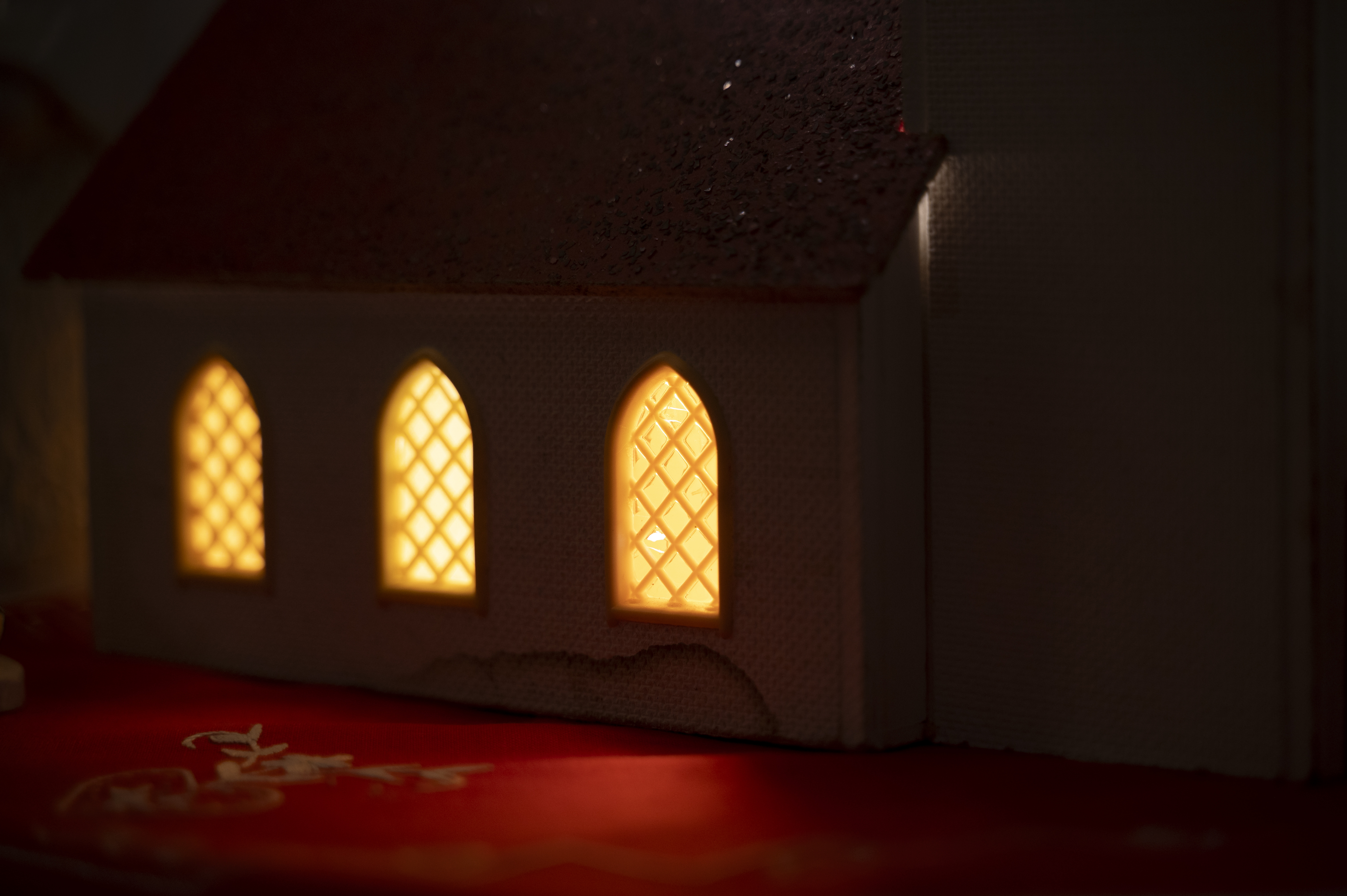 Tre upplysta kyrkfönster utifrån sett.