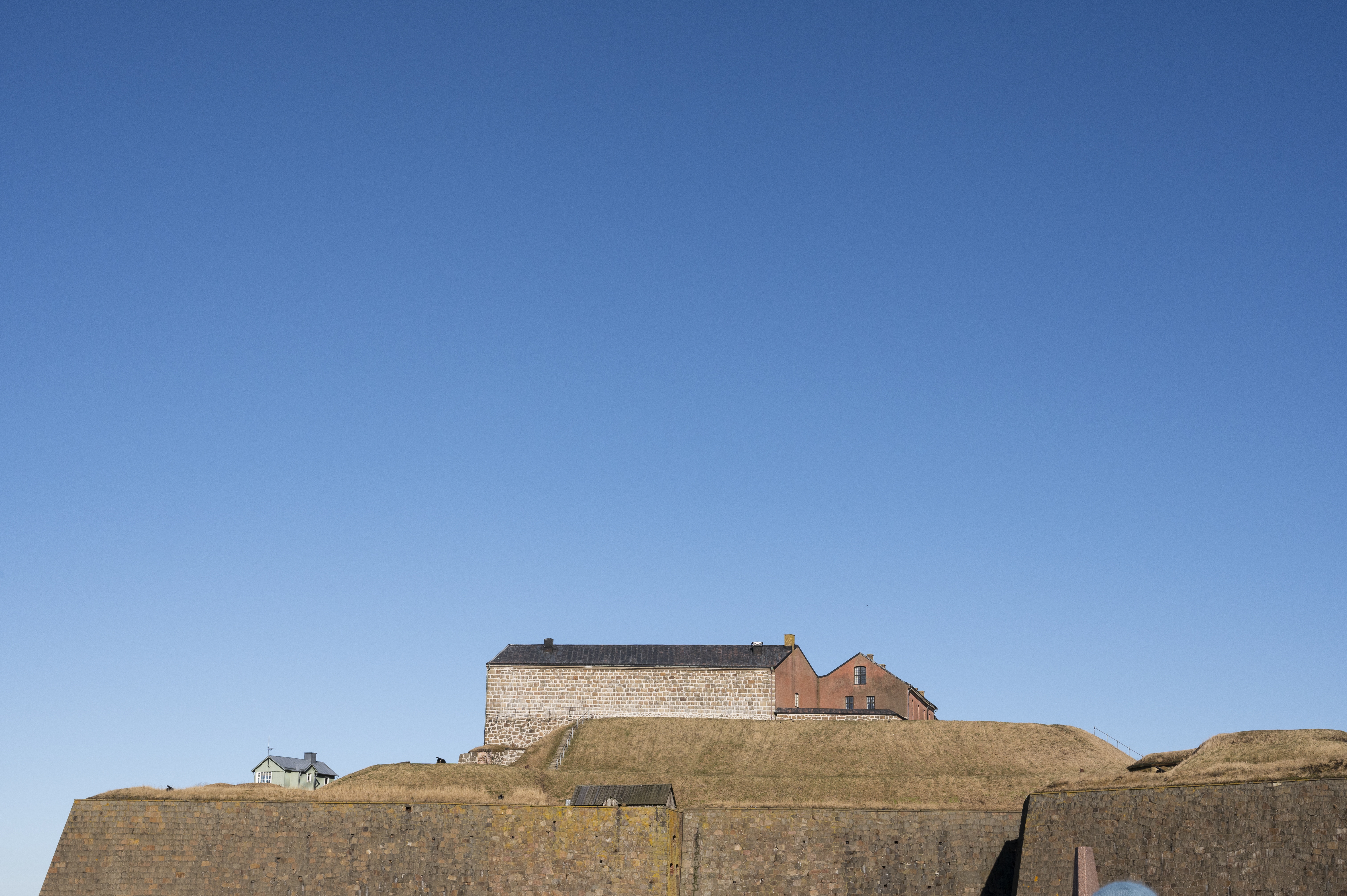 Varbergs fästning omgiven av en stenmur. Klarblå himmel.