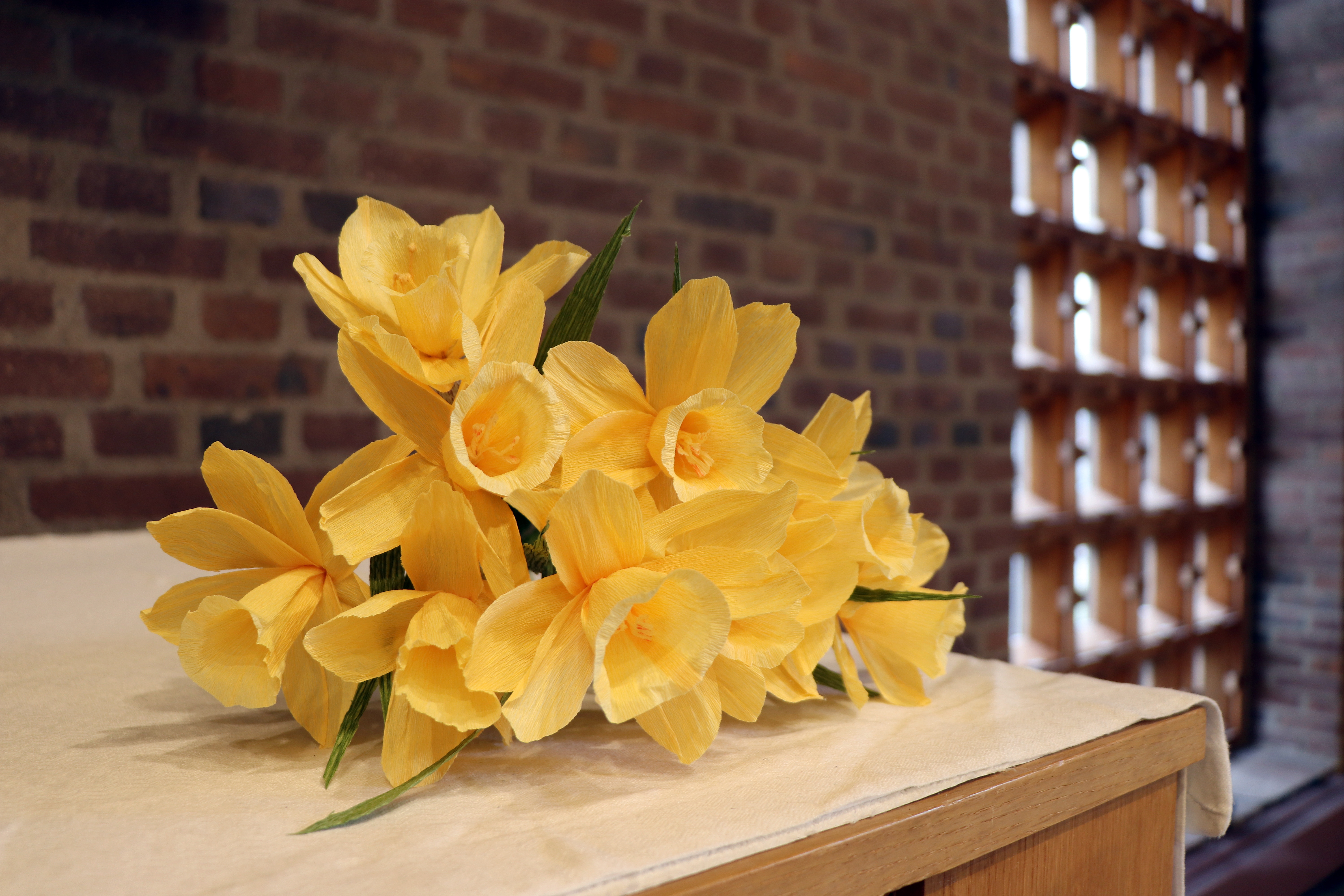 Handgjorda påskliljor på altaret i en tegelkyrka.