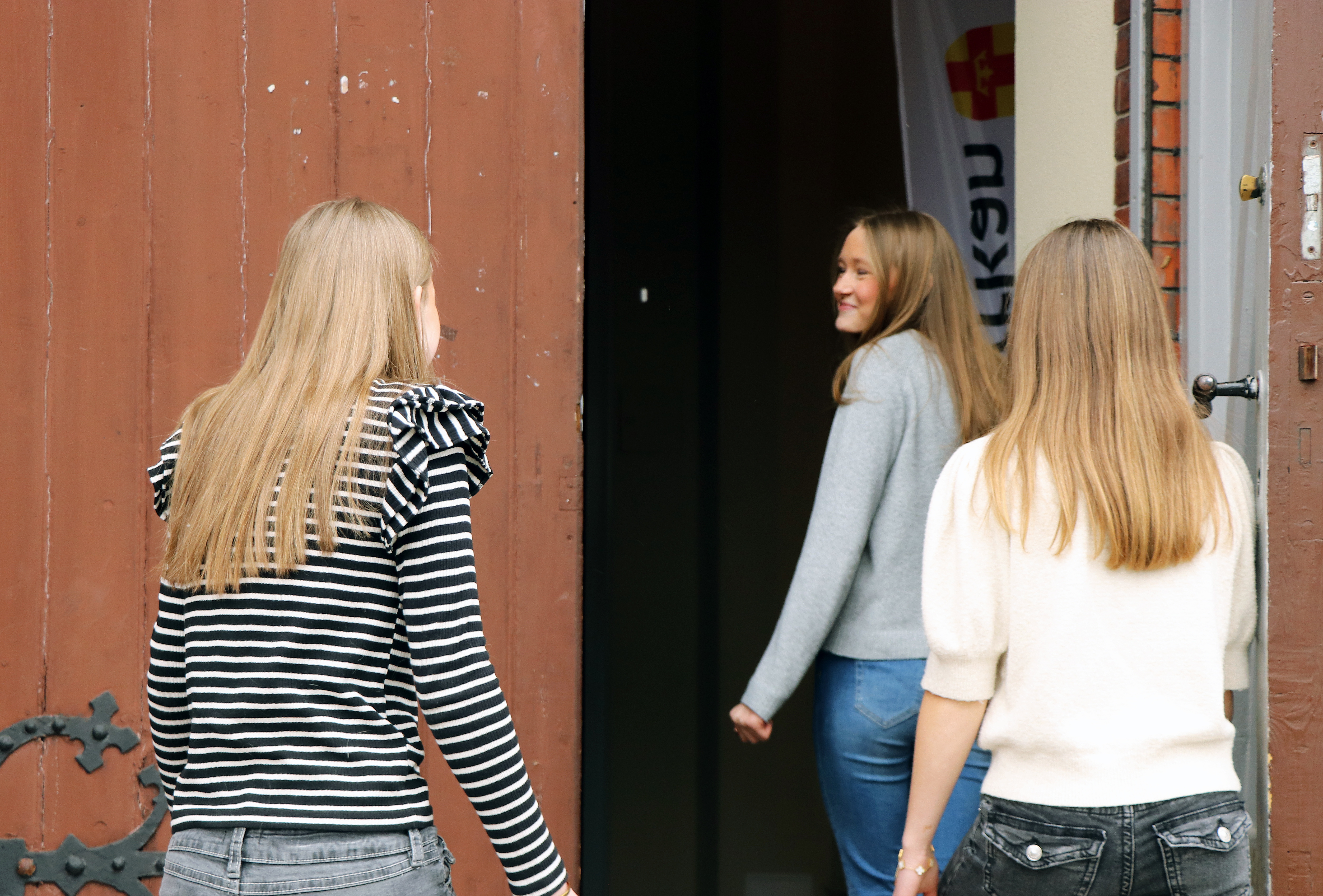 Tre tjejer går in genom en kyrkport.