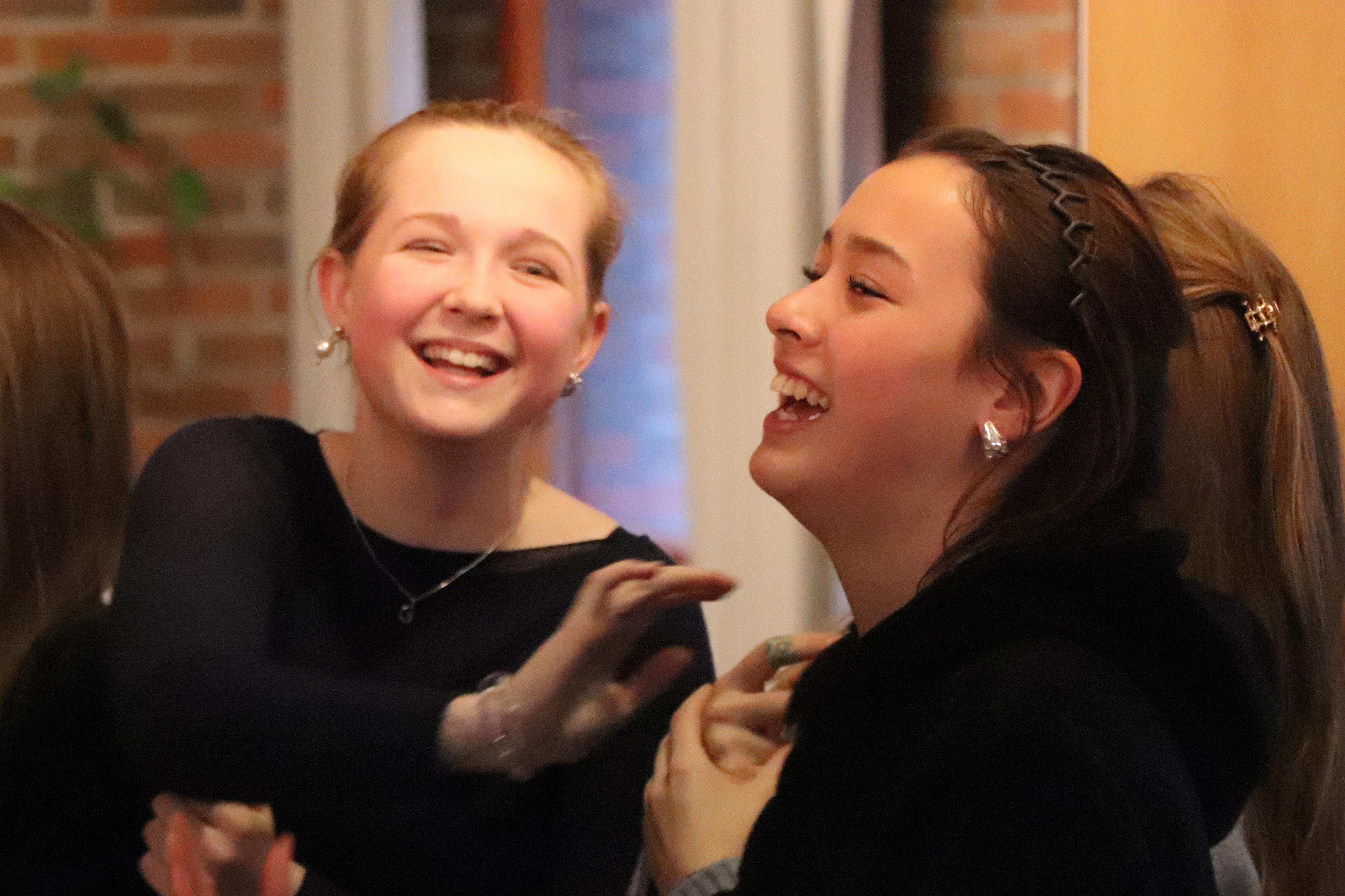 Ungdomar som skrattar och pratar med varandra i ett rum med tegelväggar.