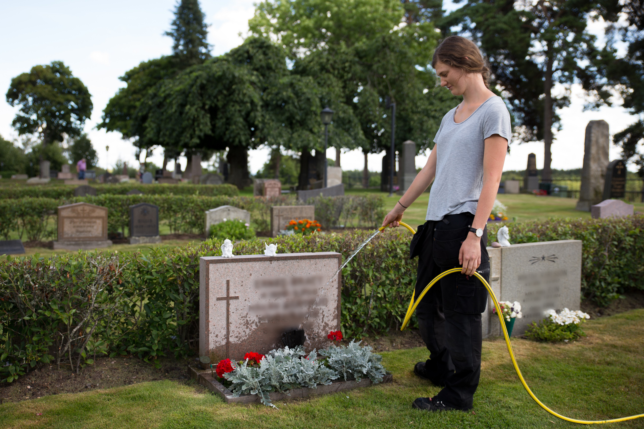 Kyrkogårdspersonal vattnar gravplats.