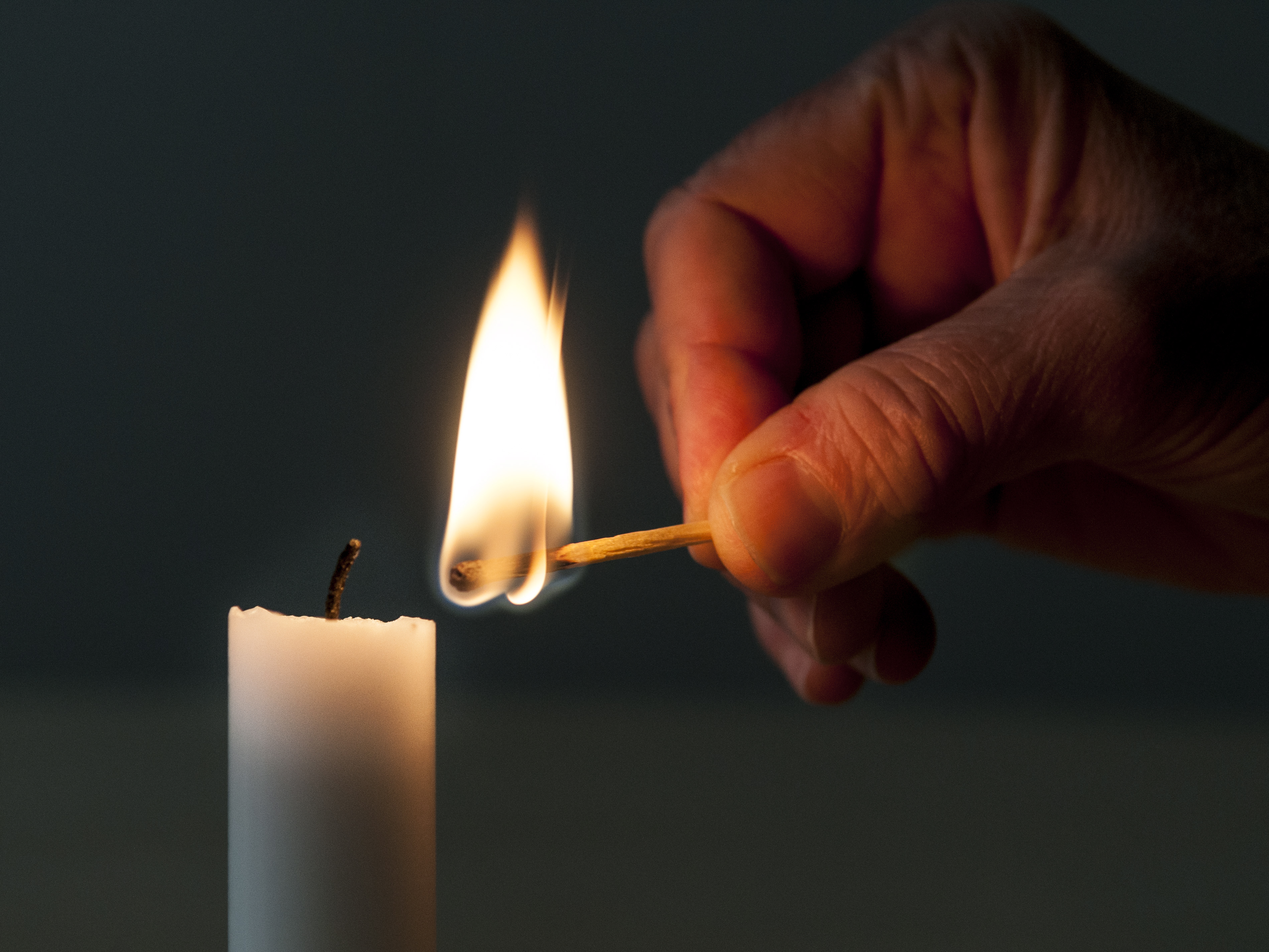 En hand som tänder ett stearinljus